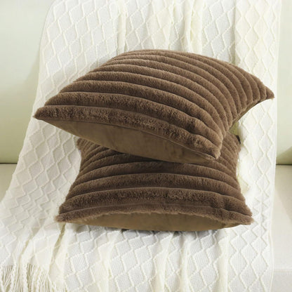 Verdelisse faux fur throw pillow covers in Brown, two covers stacked on a white knit throw