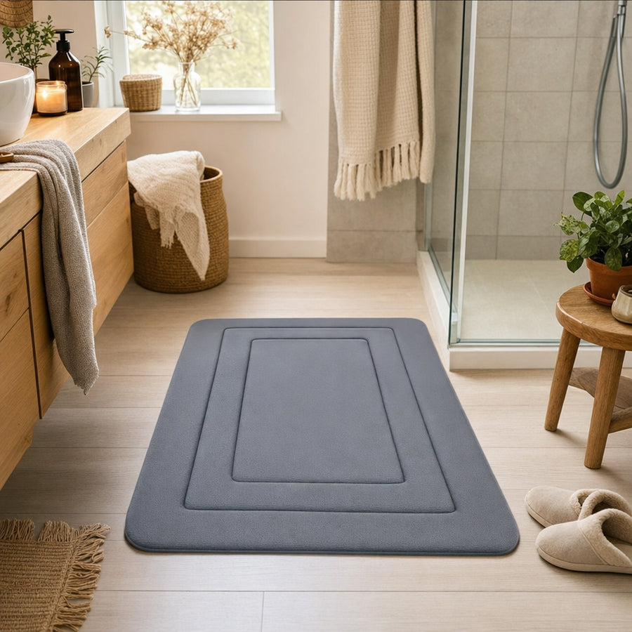 Verdelisse Absorbent Bath Mat in Deep Gray in front of a walk-in shower in a warm bathroom