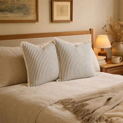 Verdelisse Striped Cushion Cover in Gray, on a made bed in a cozy bedroom